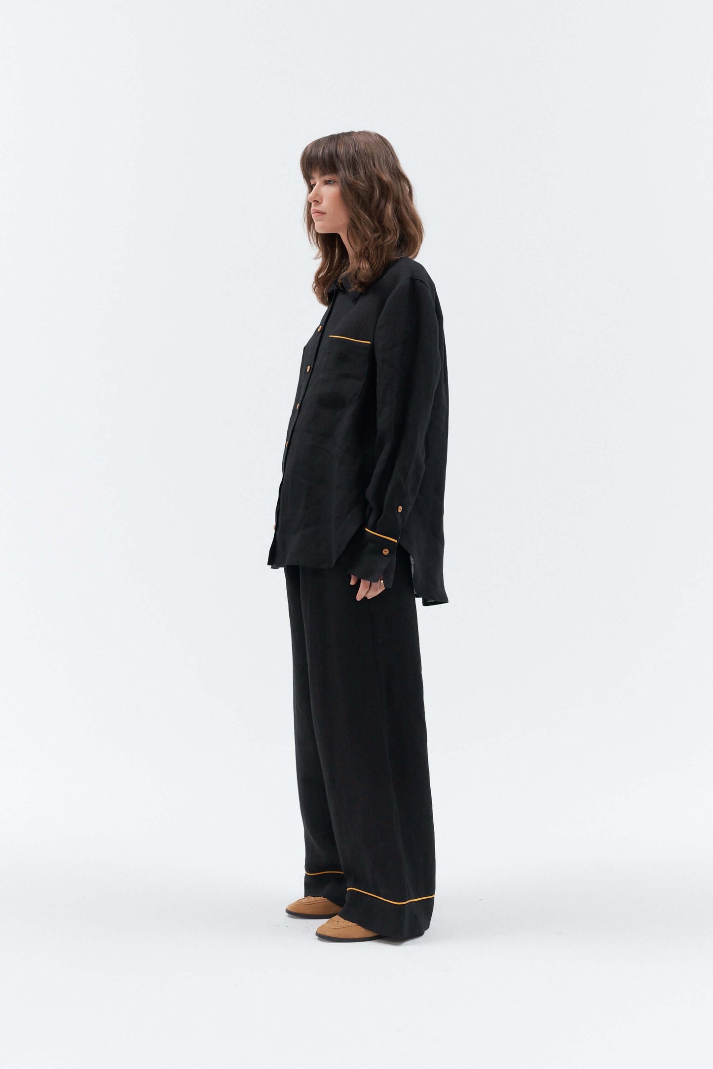 Women wearing a black linen shirt with yellow details and matching black linen pants with yellow details on a white background