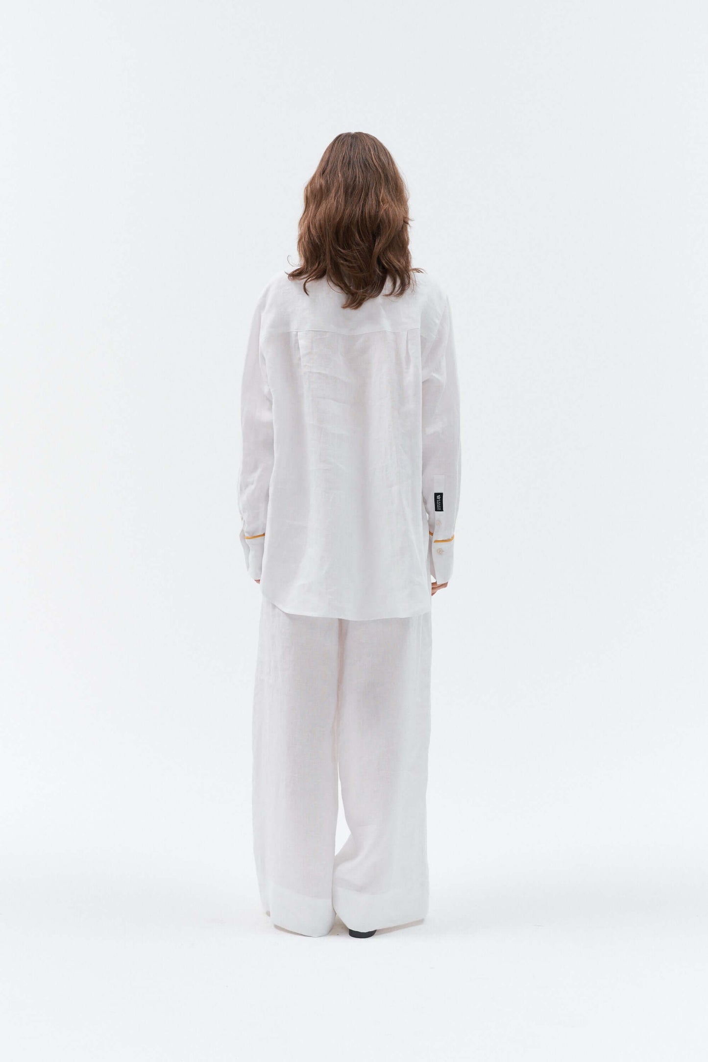 Back side of Grand Duchess women wearing white linen shirt with yellow details; oversize white linen shirt for women; women's white 100% linen shirt; long sleeved linen shirt