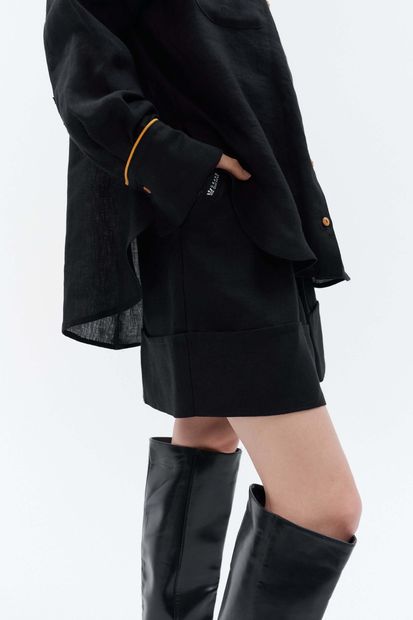 Close-up view of the black Bonita wide-leg linen shorts showing subtle cotton logo label, matching linen belt, waist coverage and textured linen fabric.