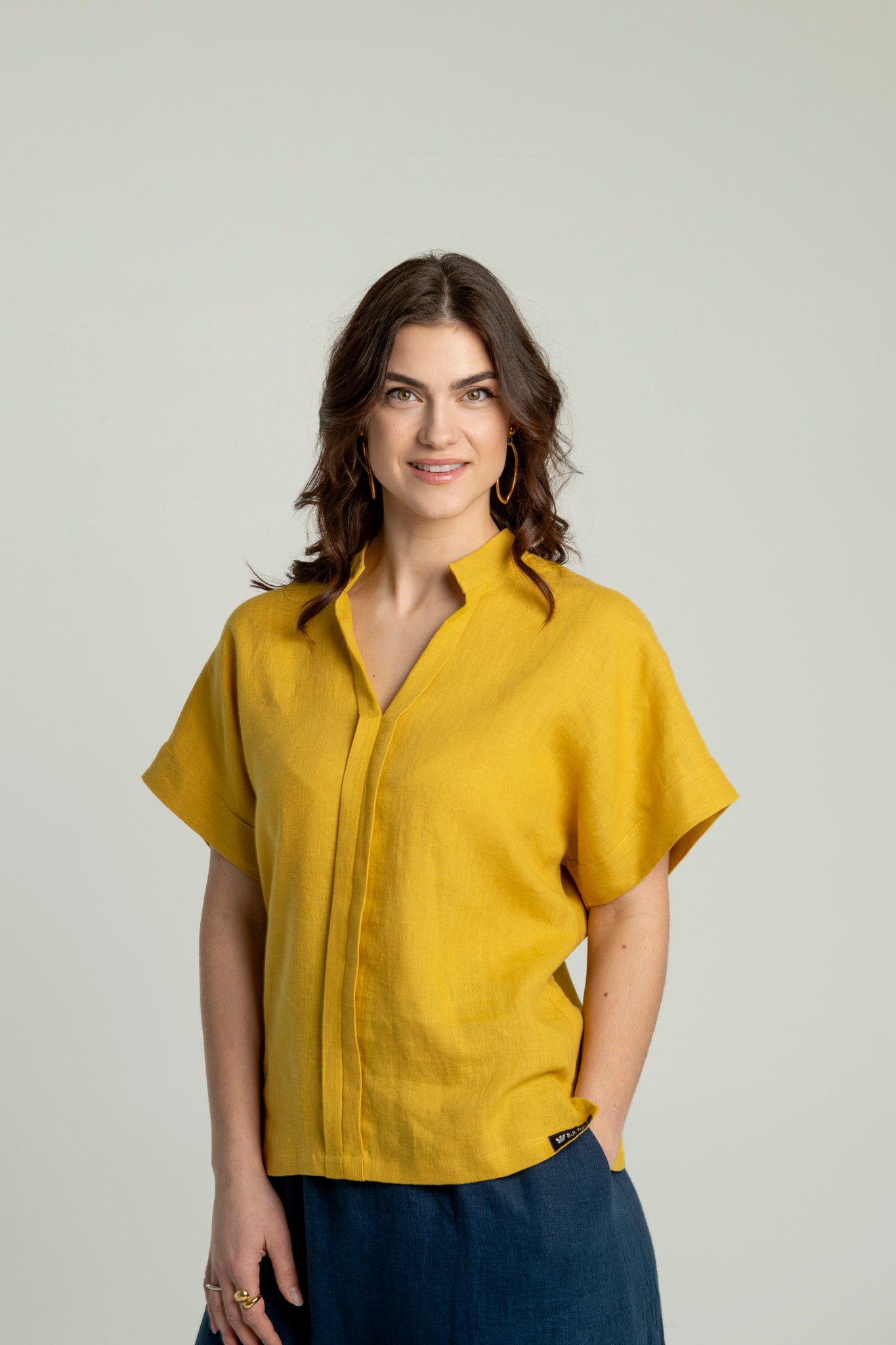 Front view of a woman wearing a mustard yellow Japanese style linen top with short sleeves and a V-neck collar.