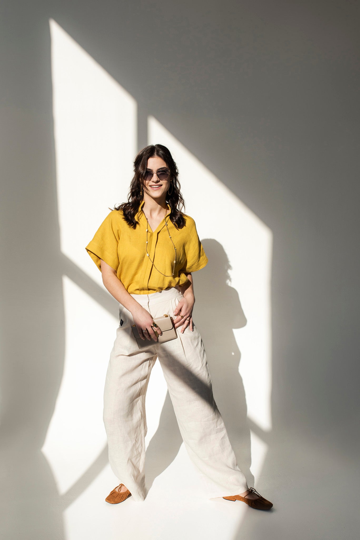 Front view of a woman wearing a mustard yellow Japanese style linen top with short sleeves and a V-neck collar, paired with a beige color linen pants Independence II.