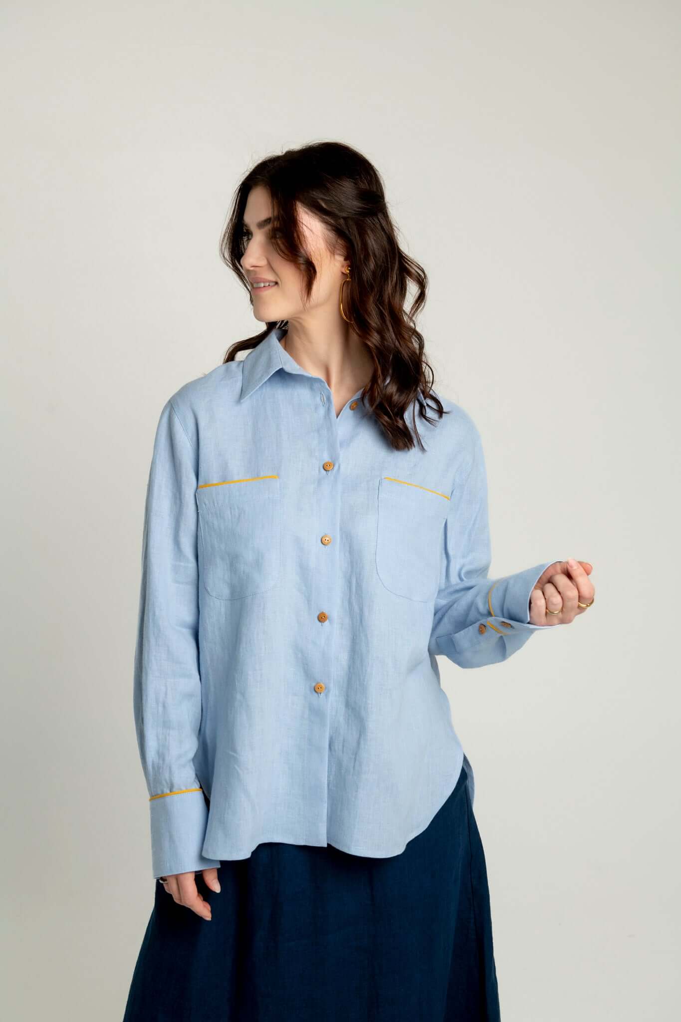 Front view of woman wearing a light blue oversized linen shirt with yellow accents Brillante on a plain background