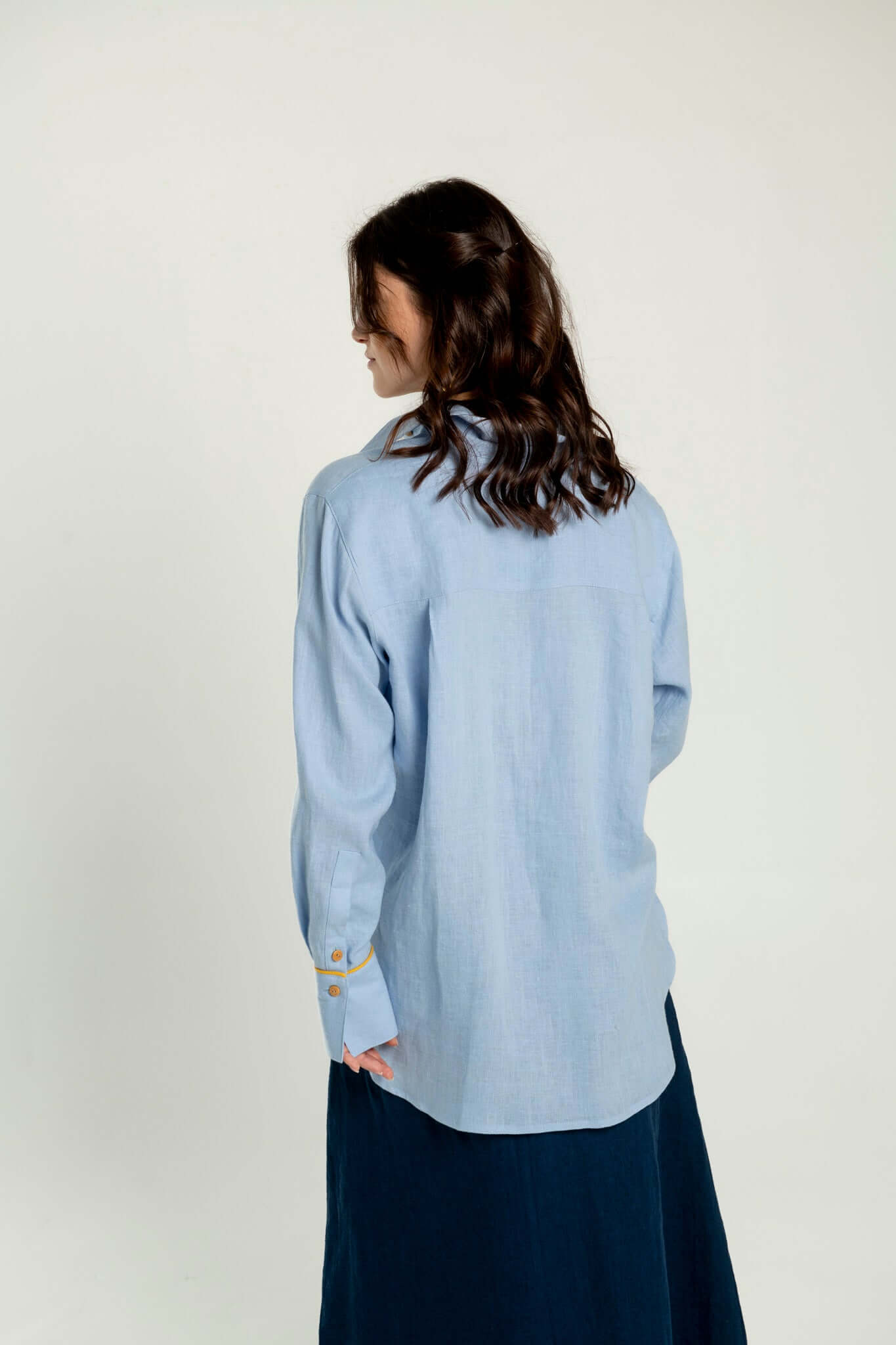 Back side of women wearing baby blue oversized linen shirt.