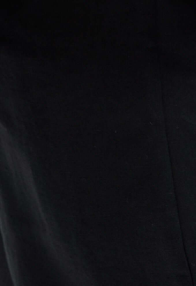 Close-up of a solid black linen fabric, showcasing texture and breathability of Adventurer II - women’s ruffled strap linen top.