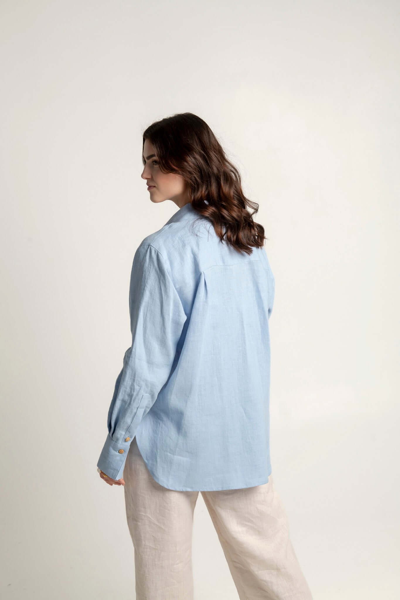 Woman wearing a light blue long sleeve oversized linen shirt Brillante, showcasing a relaxed style.