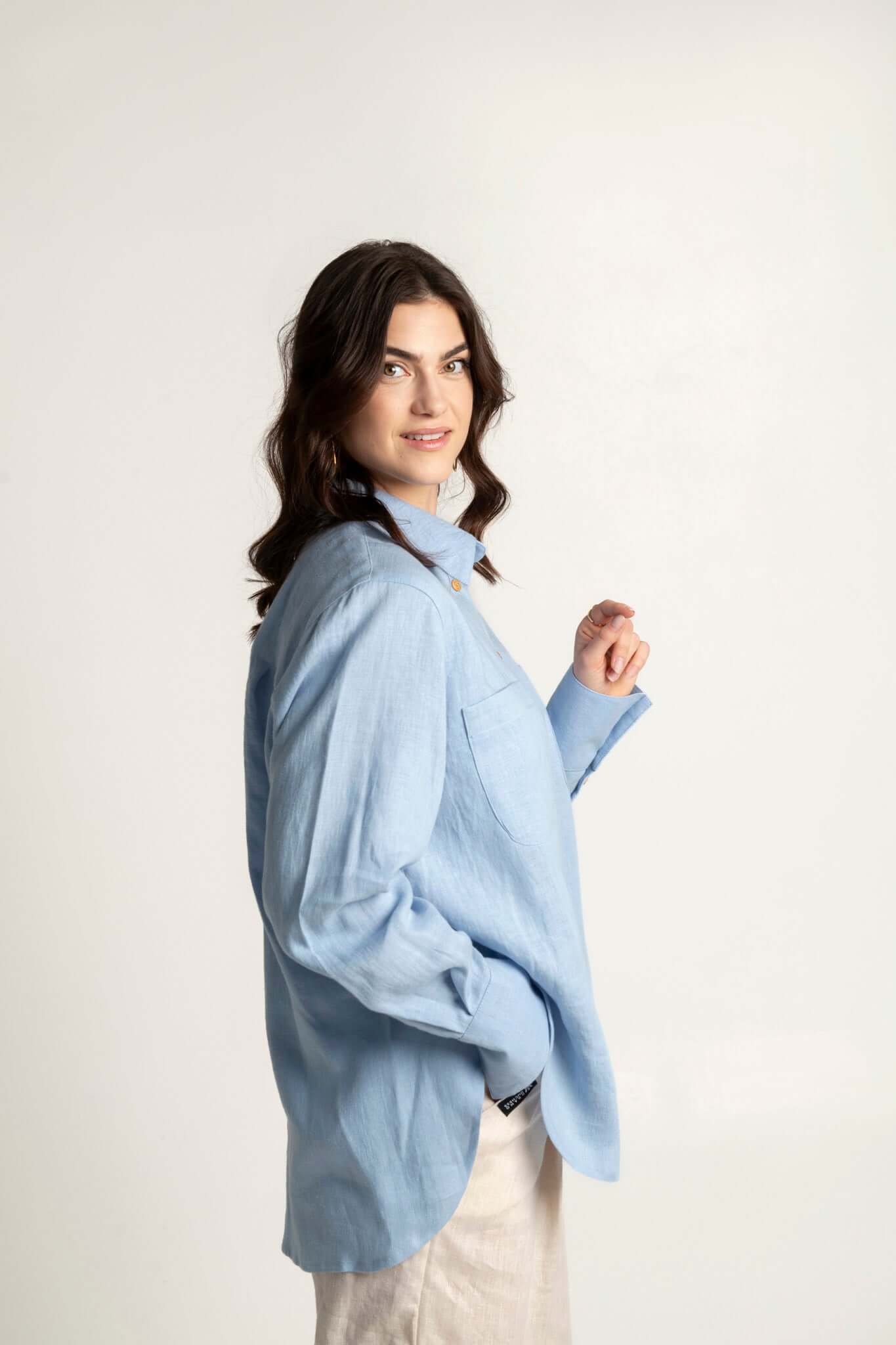 Model wearing a long sleeve oversized linen shirt in light blue, showcasing comfort and elegance.