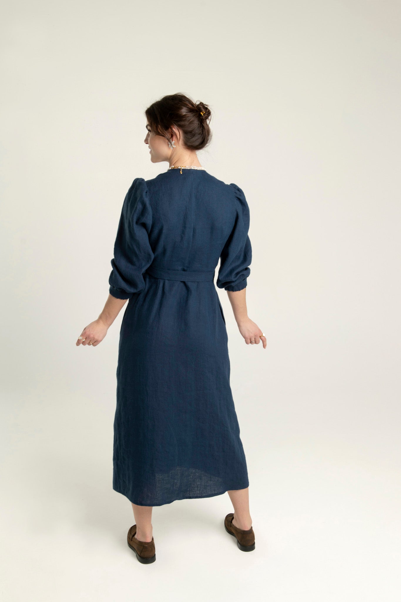 Navy blue Riviera crossover fit-and-flare linen midi dress with side pockets, worn by a woman, perfect for elegant and breathable summer fashion.