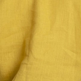 Close-up texture of mustard yellow linen fabric from a women’s linen robe
