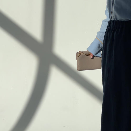Video of a woman wearing a navy blue linen maxi skirt Soho with side pockets and elastic waistband, styled for an elegant urban look, moving slowly in a room with dappled light.
